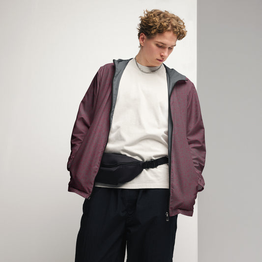 Male model wearing a maroon windbreaker jacket over a white shirt with black pants on a light gray background