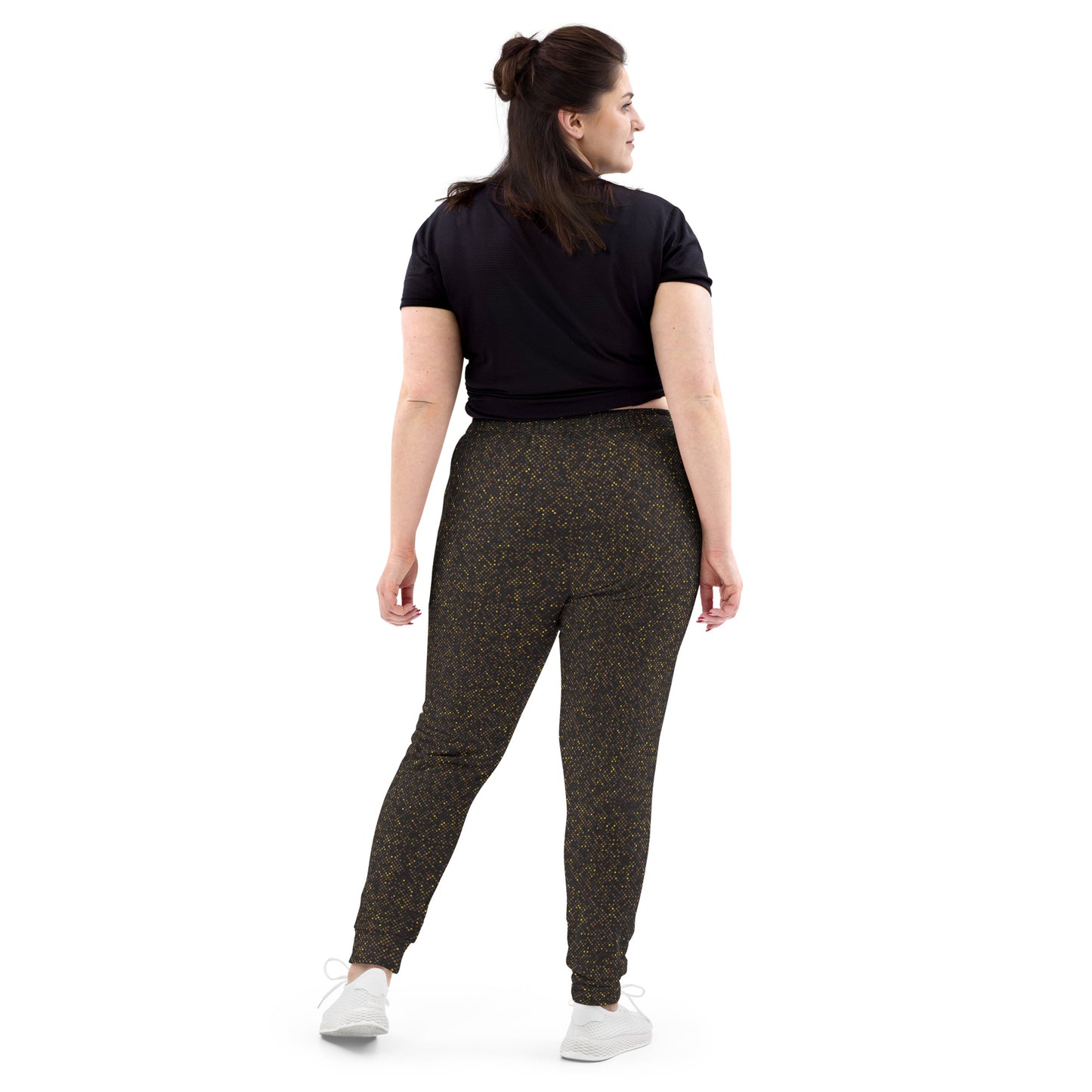 Back view of woman wearing black t-shirt and polka dot patterned slim fit jogger pants on a white background