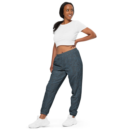 Woman wearing a white crop top and blue track pants on a white background