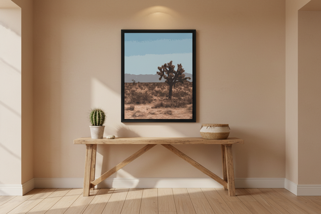 Framed joshua tree desert landscape print on a wall above a wooden table with decor items.