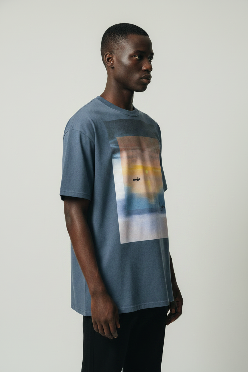 side view of model wearing a blue t-shirt with a sunset graphic design