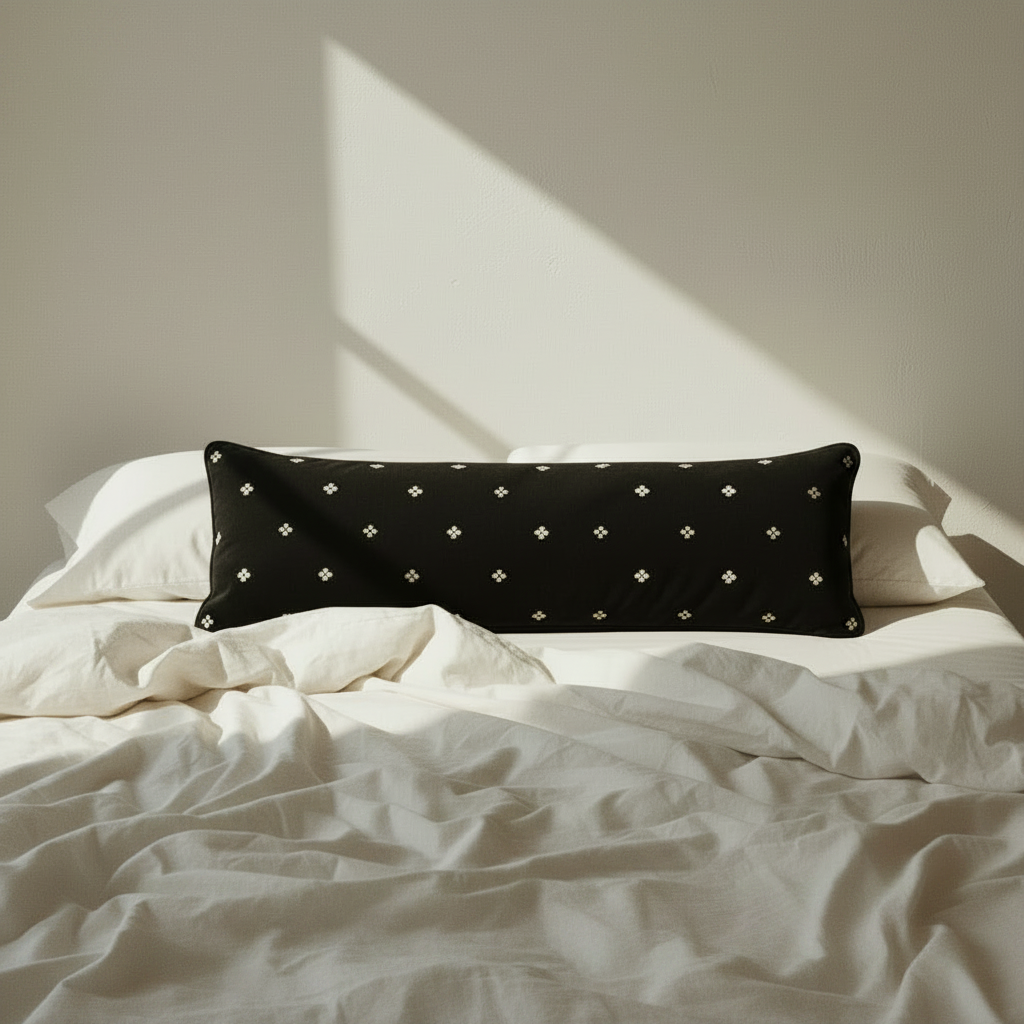 black velvet bolster pillow on a bed 