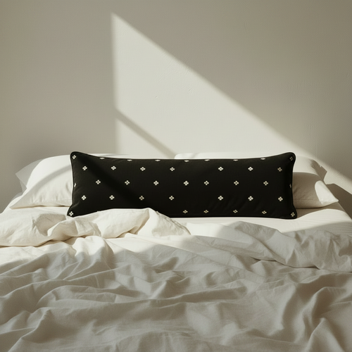 black velvet bolster pillow on a bed 