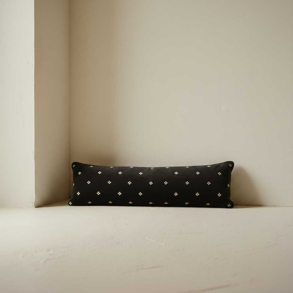 black velvet bolster pillow against a wall 