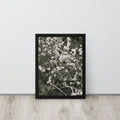 Framed artwork of floral cherry blossom branches on a white wall with wooden floor.