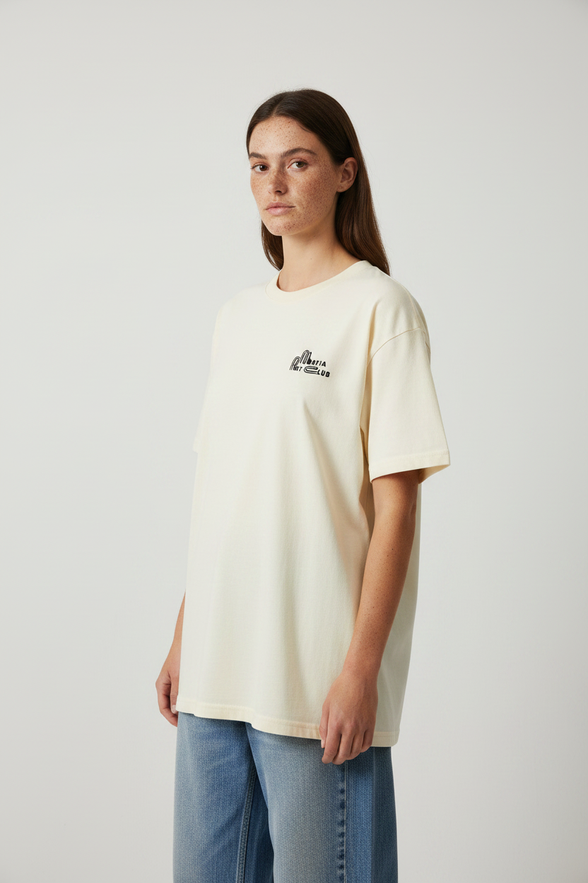 side view of female model wearing a faded oversized beige t-shirt with ‘Mirfia Art Club’ text 