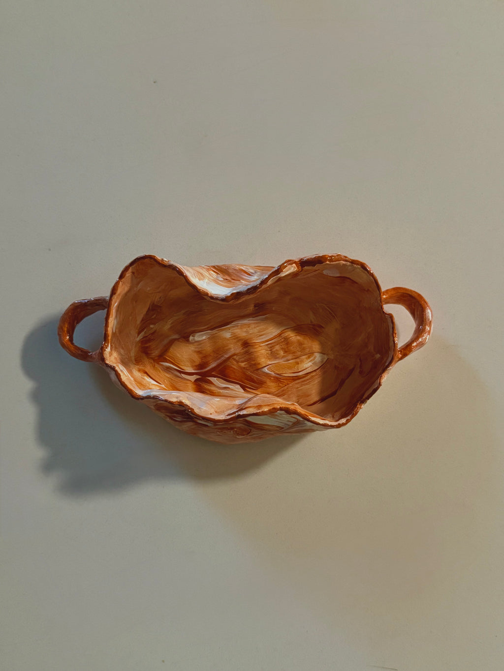 A handmade ceramic dish with a rustic, hand-painted finish and two side handles 
