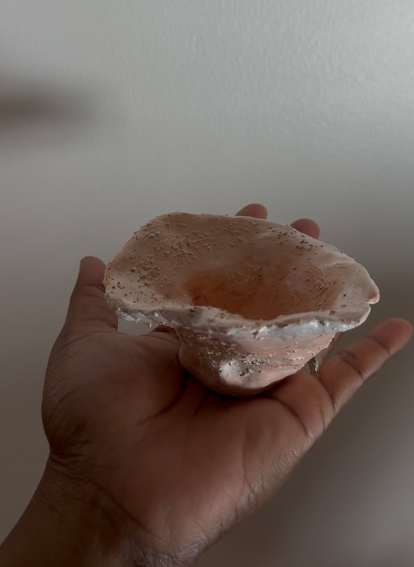 A hand holding a small, organic-shaped decorative textured bowl
