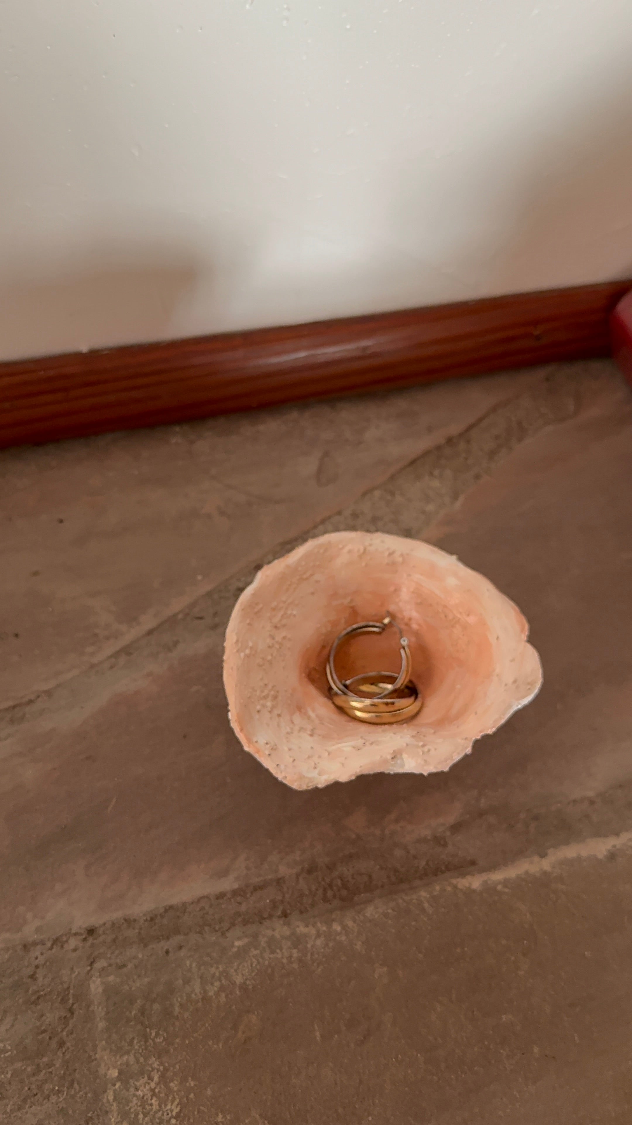 gold earrings displayed inside a small, handmade sculptural ceramic trinket bowl