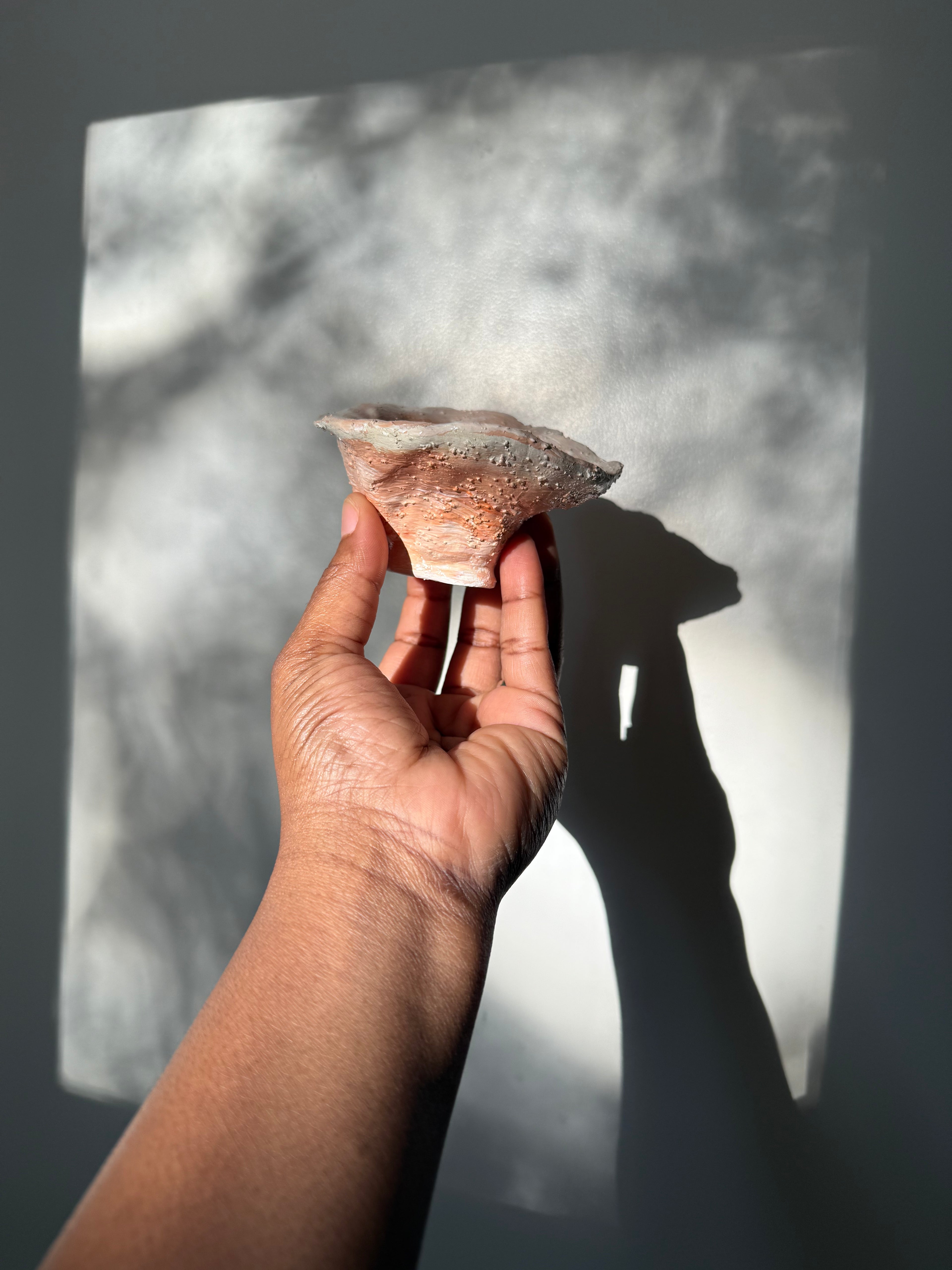 A hand holding a small, textured decorative ceramic catchall bowl