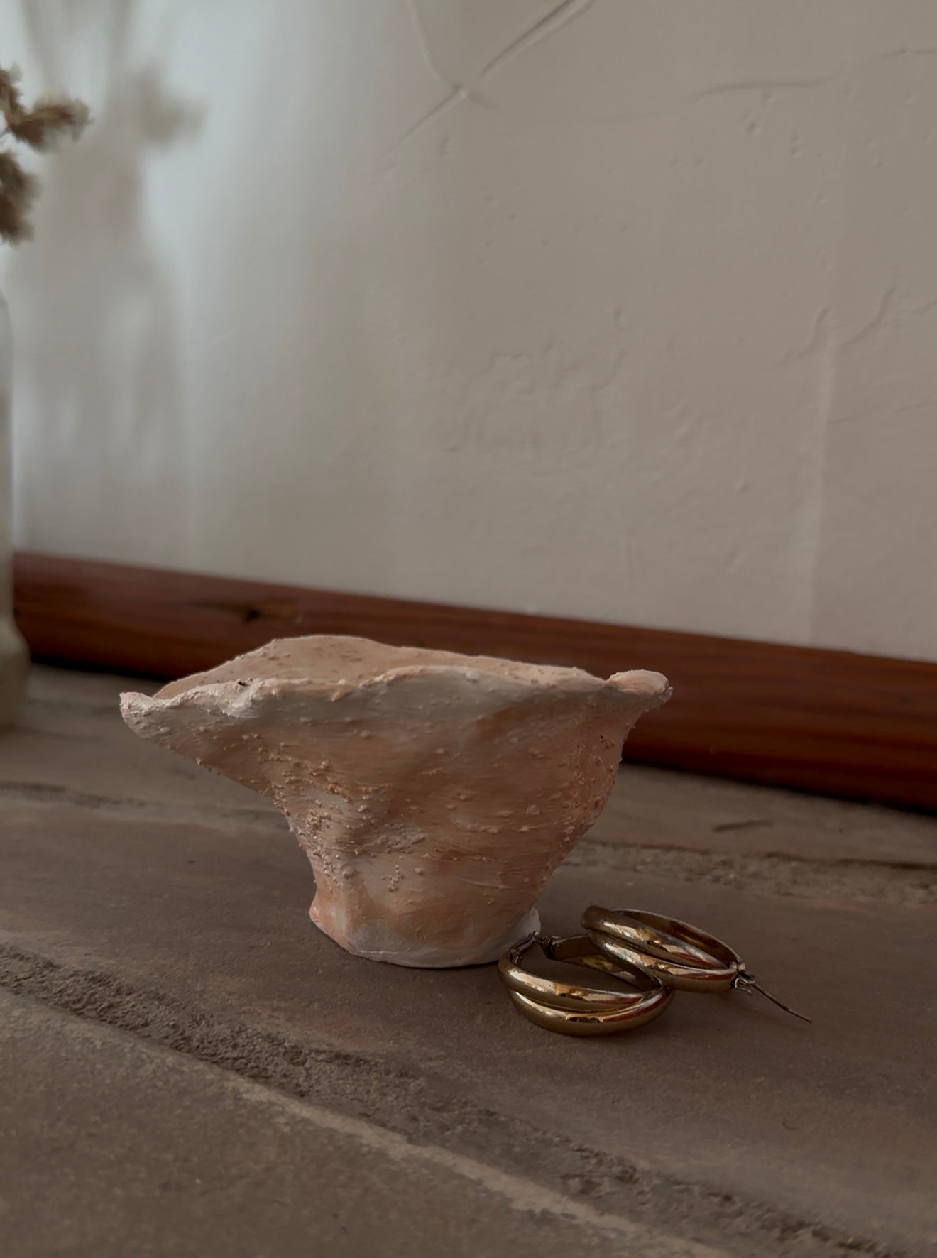 A textured, organic-shaped ceramic trinket bowl on a stone surface
