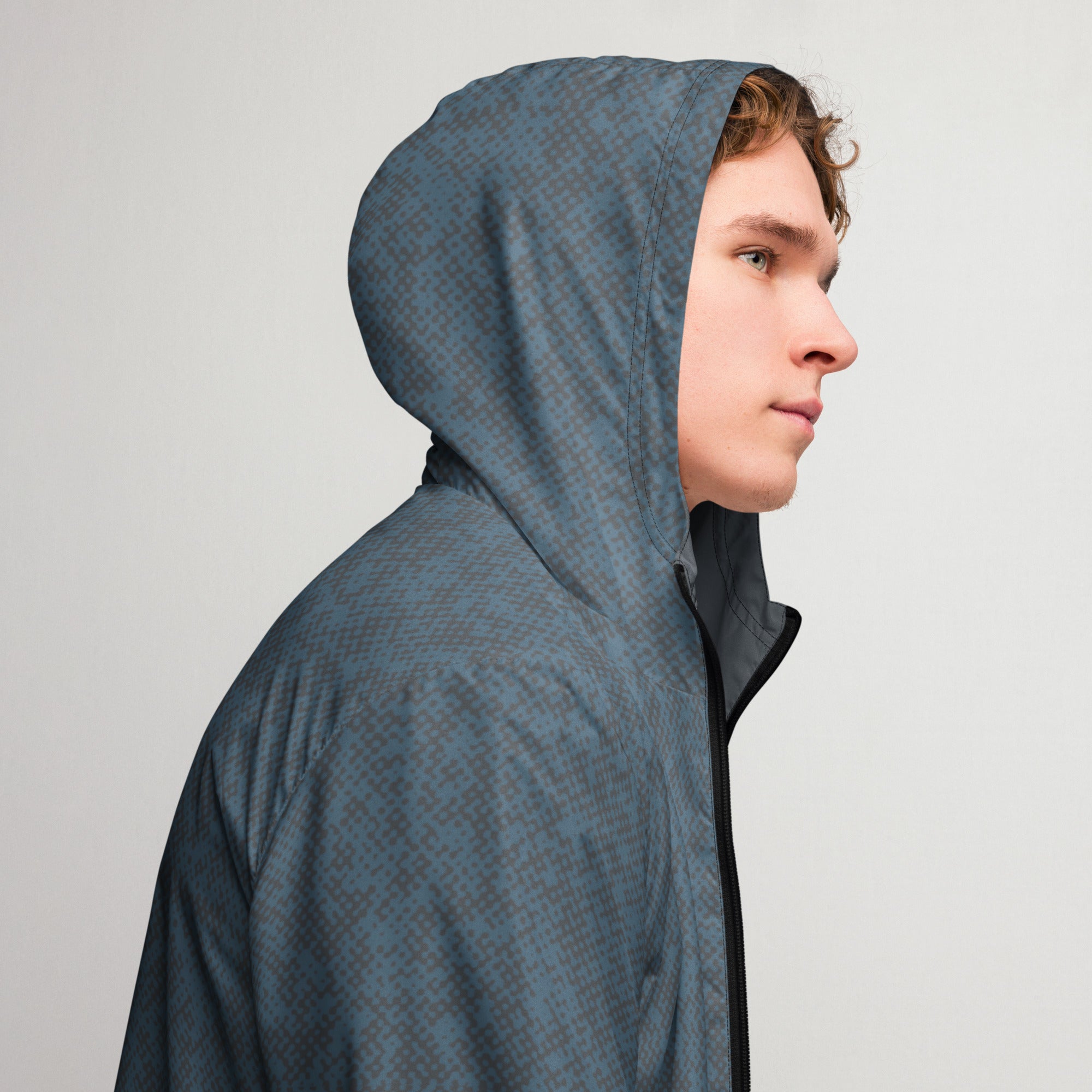 Person wearing a blue windbreaker jacket hoodie against a plain background