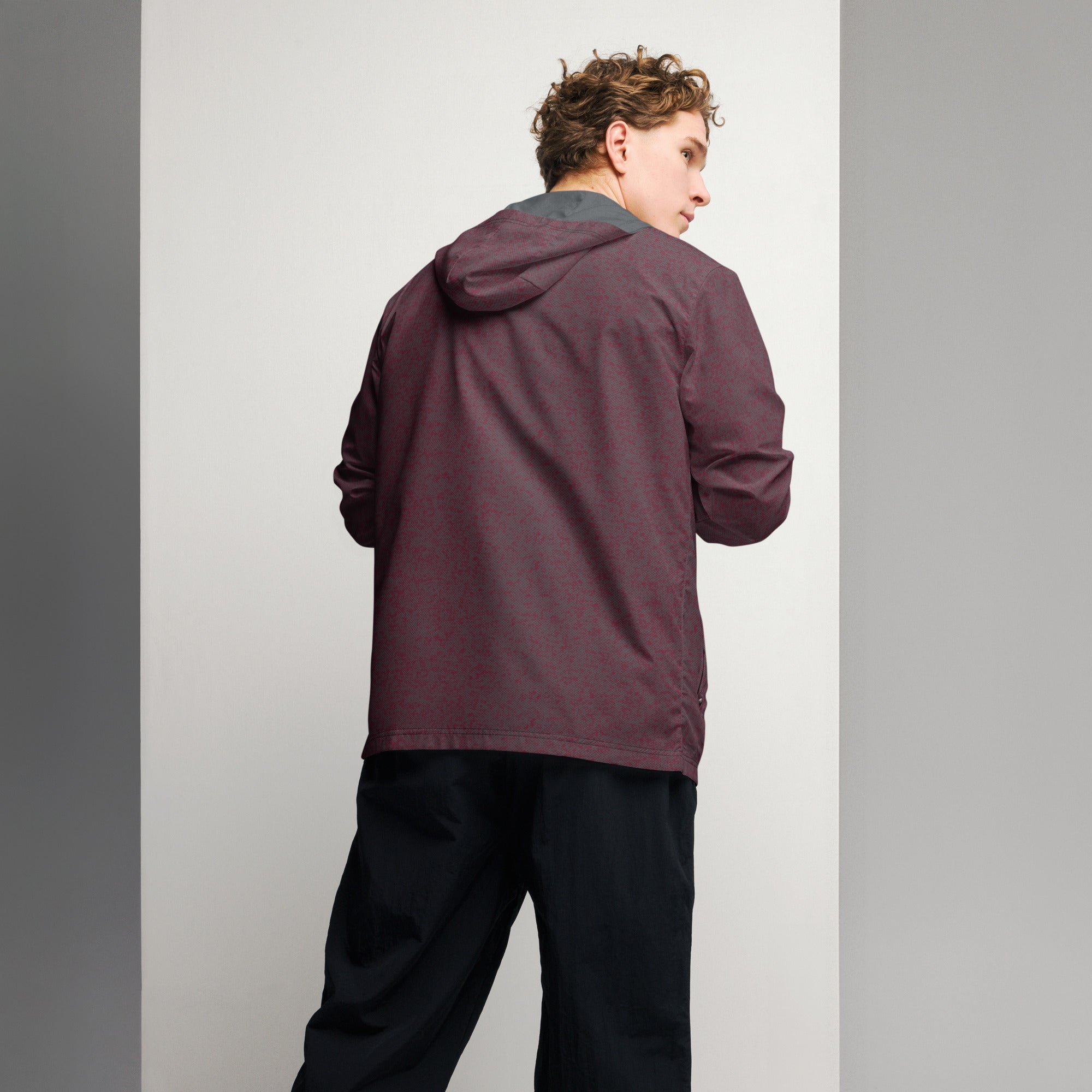 Back view of male model wearing a hooded maroon windbreaker jacket against a plain background