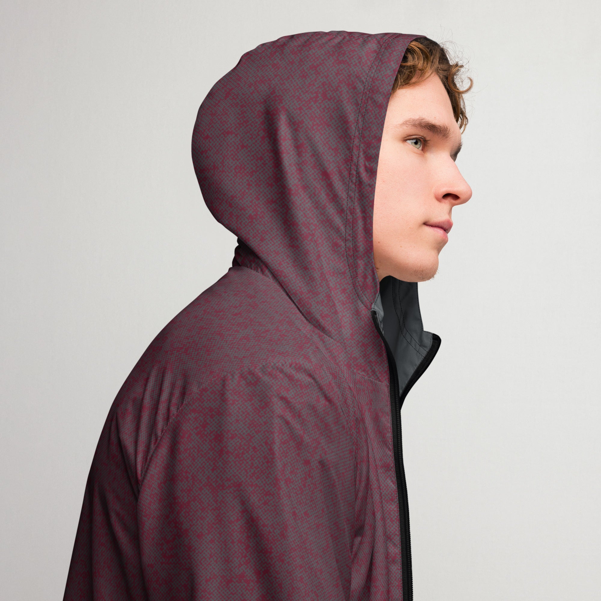 Man wearing a maroon hooded windbreaker jacket against a plain background