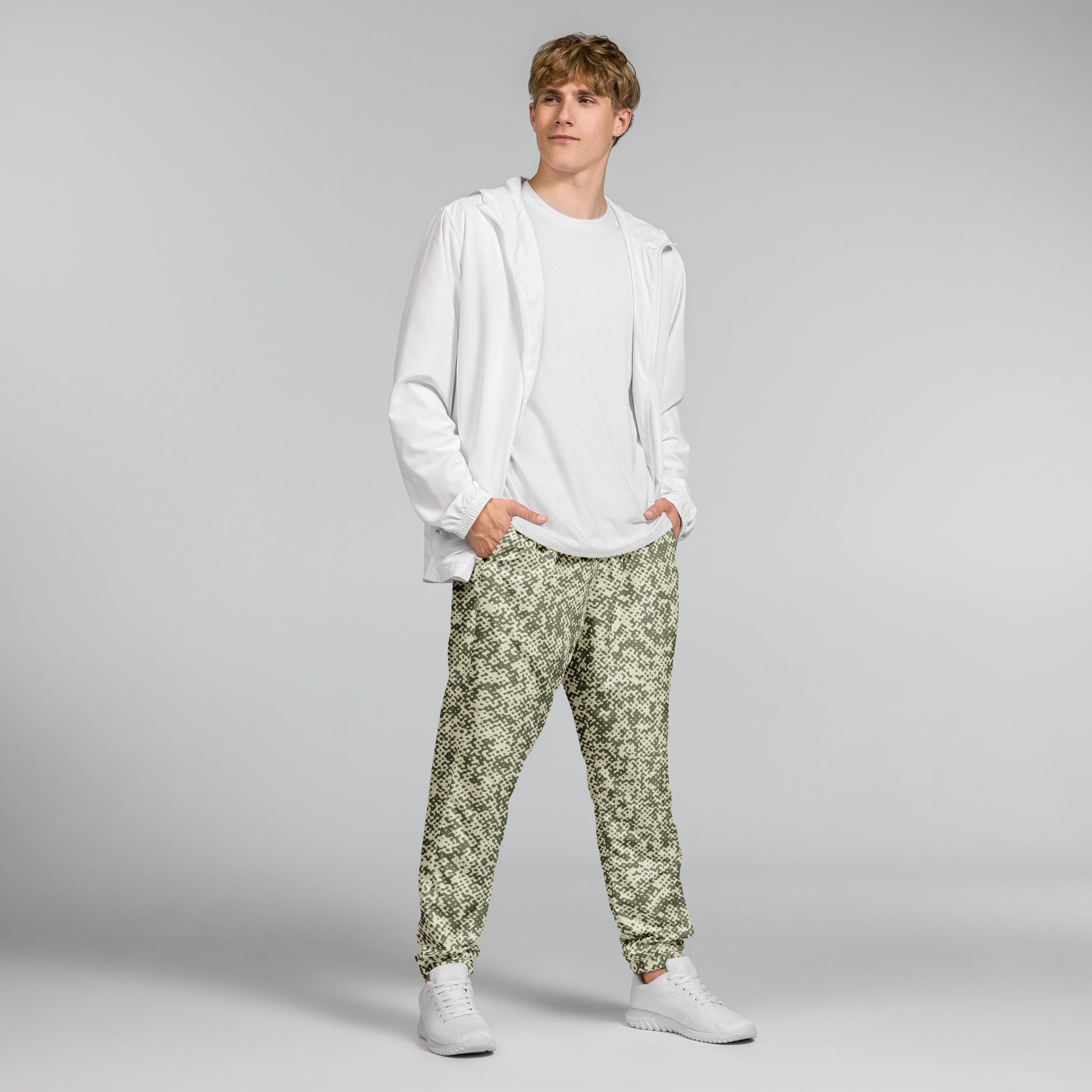 Person wearing a white hoodie and patterned green track pants on a gray background