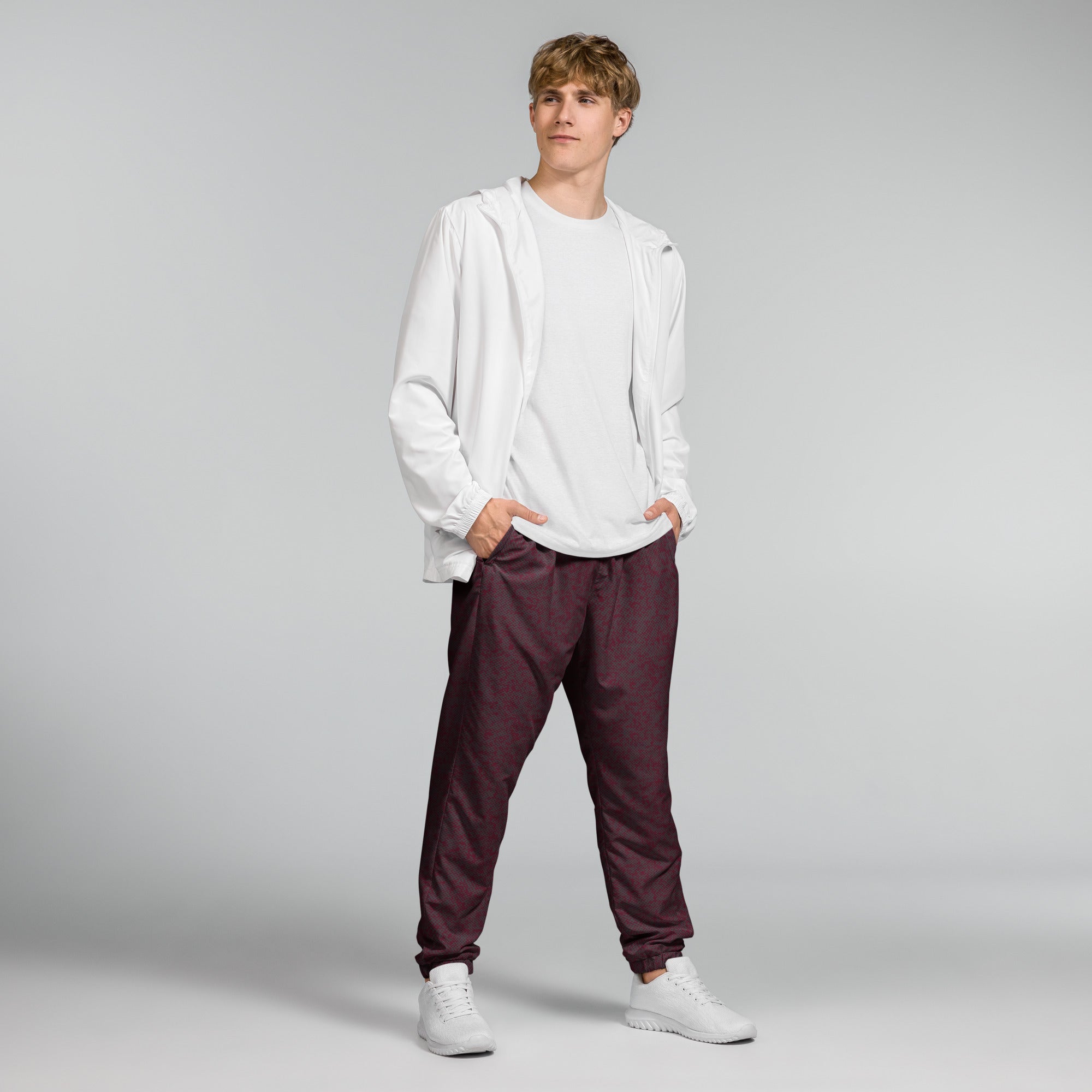 Male model wearing a white hoodie and maroon track pants on a gray background