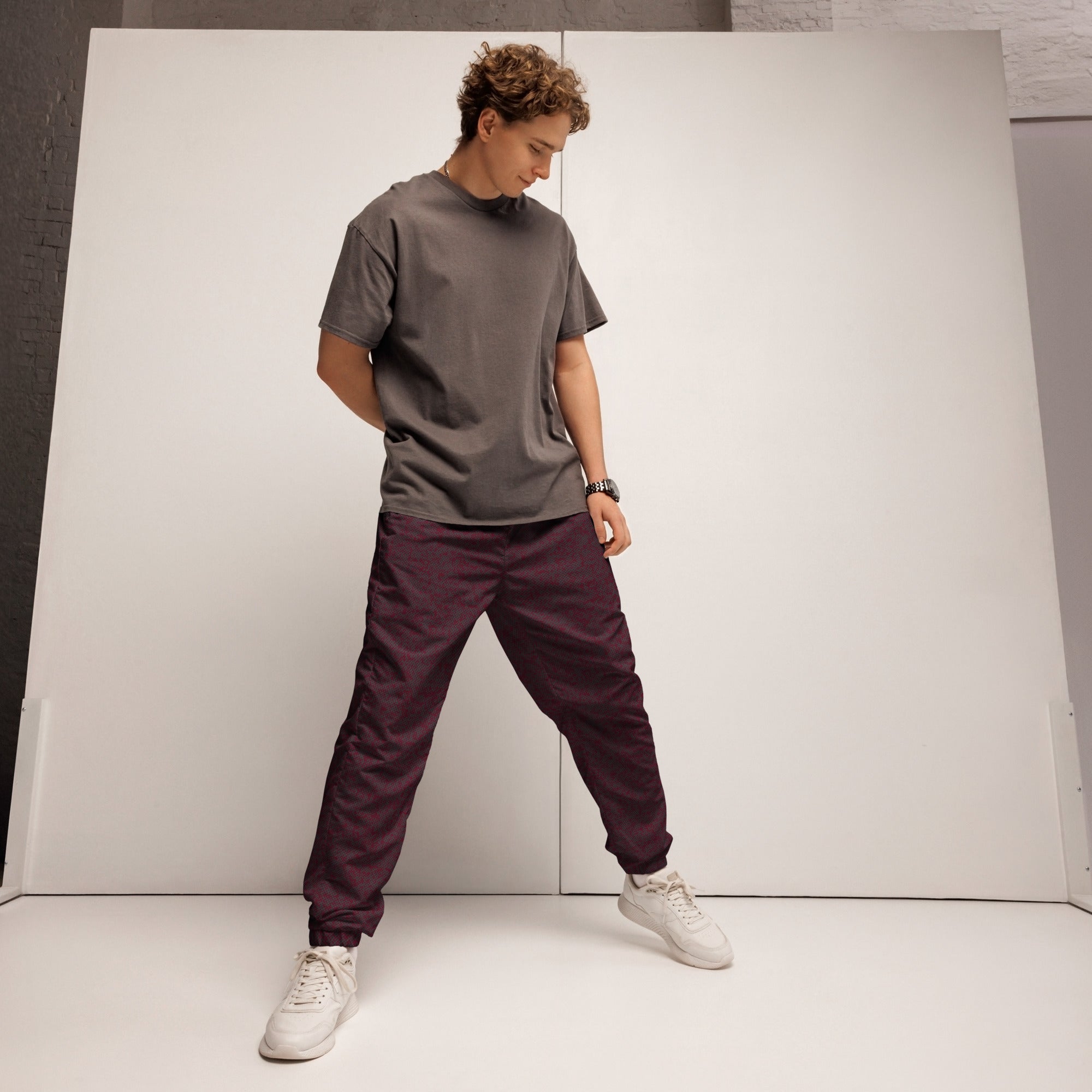 Person wearing a gray t-shirt, maroon track pants, and white sneakers against a plain background