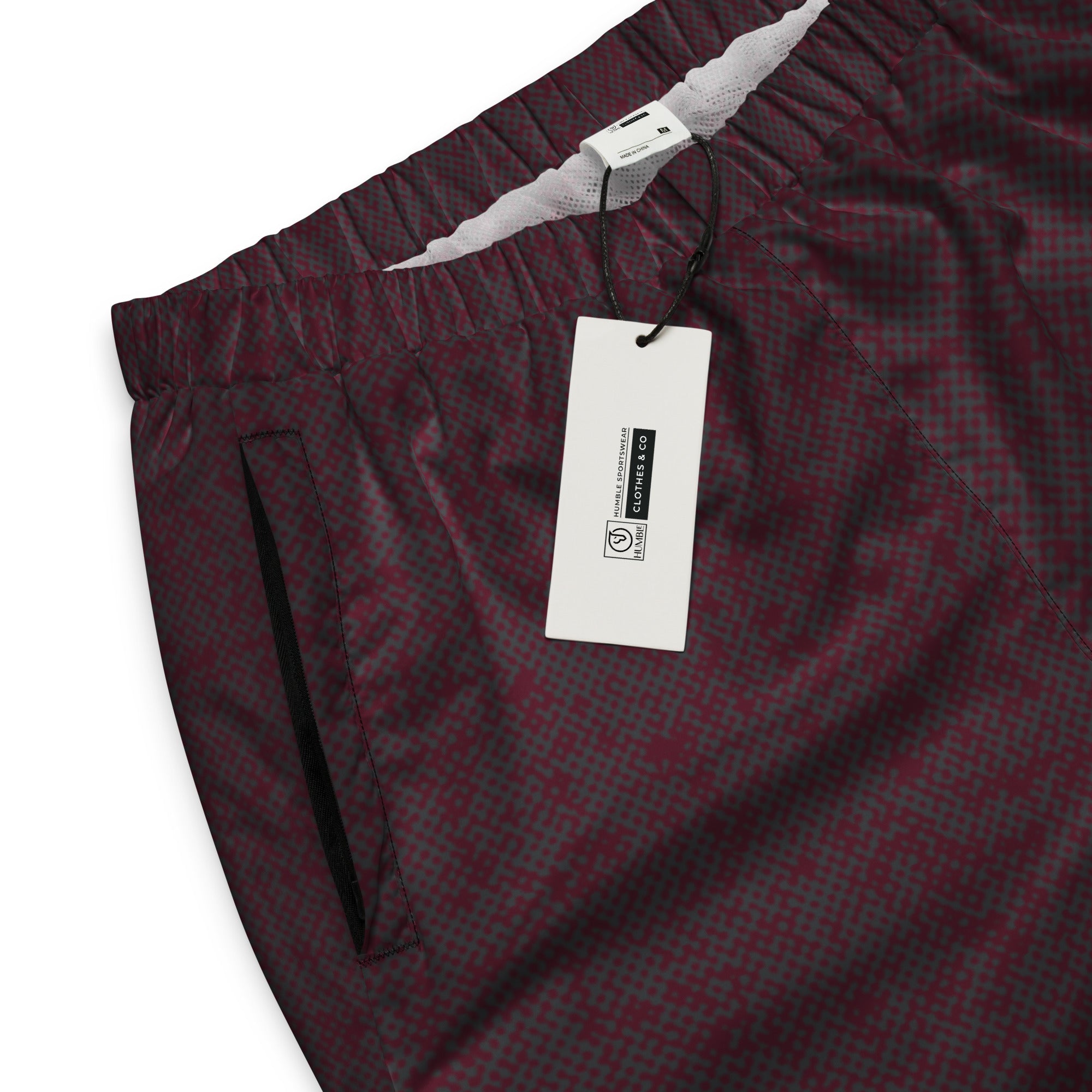 Maroon checkered track pants with a tag on a white background