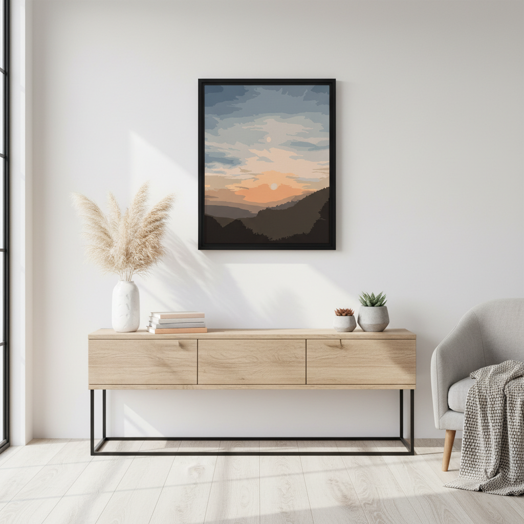 Framed artwork of a sunset over mountains on a wall above a wooden console table.