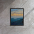 Framed artwork of a mountain landscape with a sunset on a textured wall.