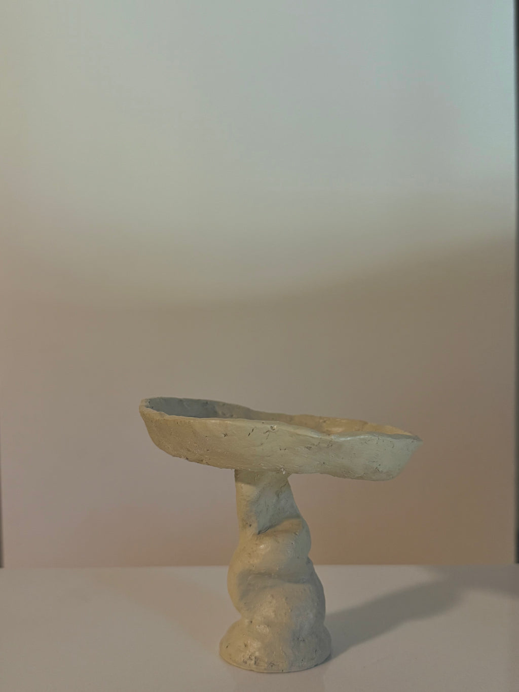 Organic form decorative bowl with an earthy neutral finish and twisted pedestal base.