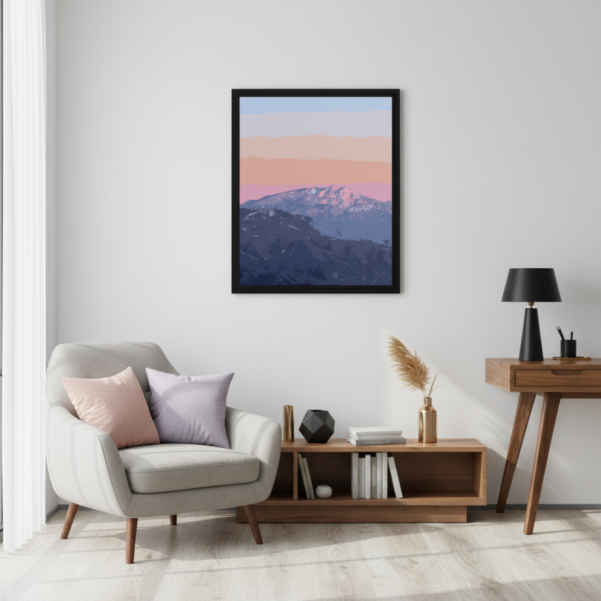 Framed mountain landscape print on a wall above a chair with cushions in a living room setting.