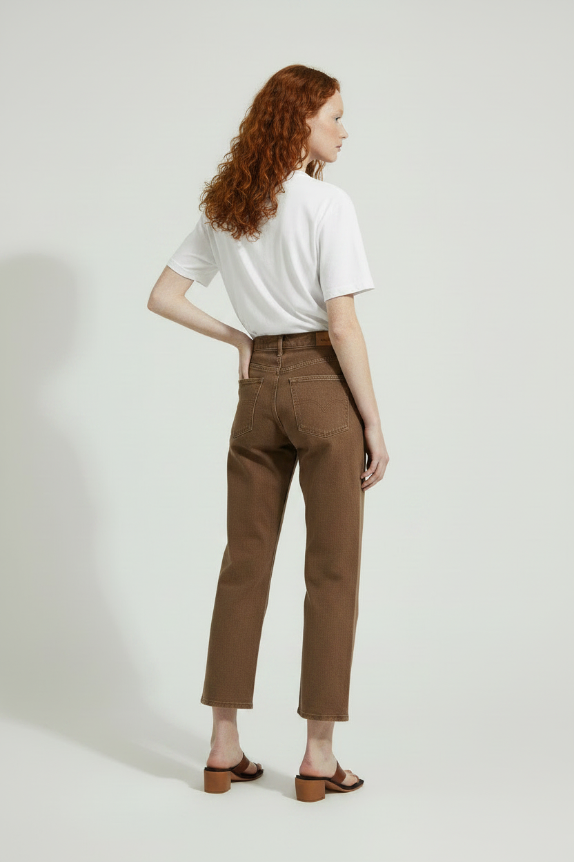 back view of model wearing a white 100% cotton t-shirt and brown pants on a plain background