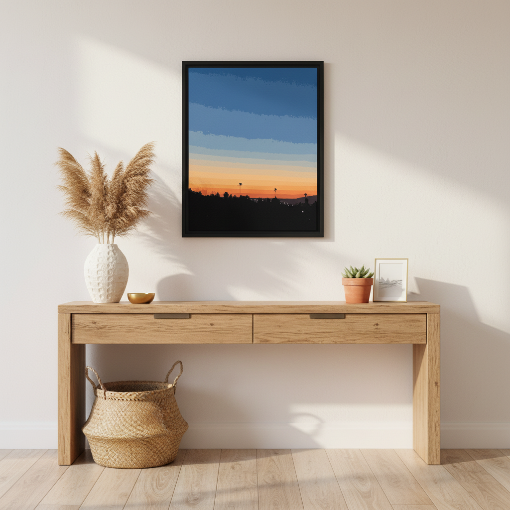 Wooden console table with decorative items against a white wall with a framed sunset palm trees wall art.