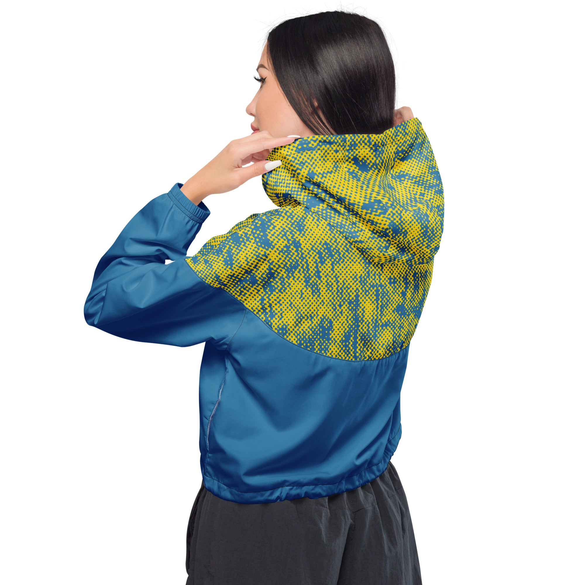 woman wearing a blue and yellow cropped windbreaker jacket with patterned hood on a white background
