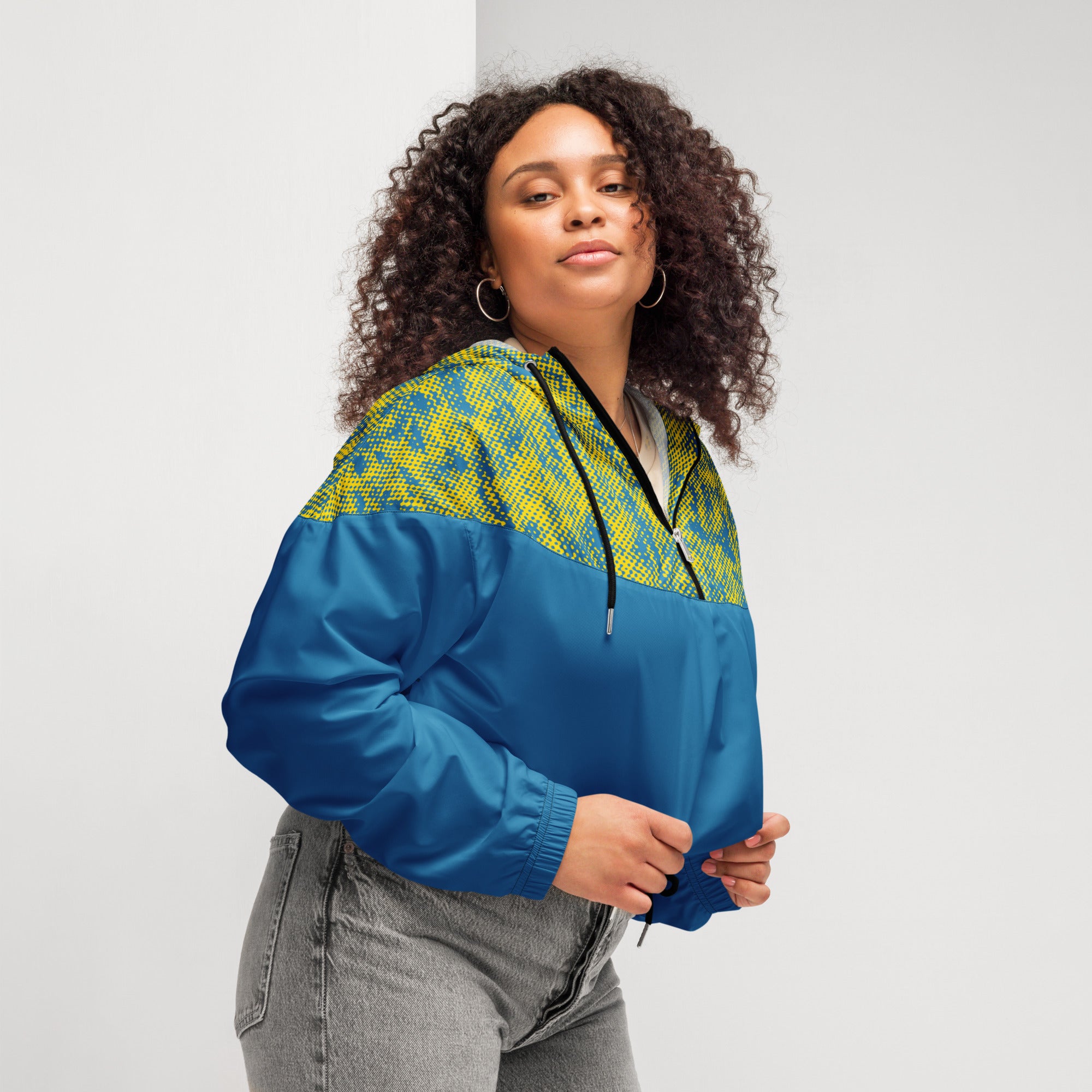 Woman wearing a blue and yellow patterned cropped windbreaker jacket against a plain background