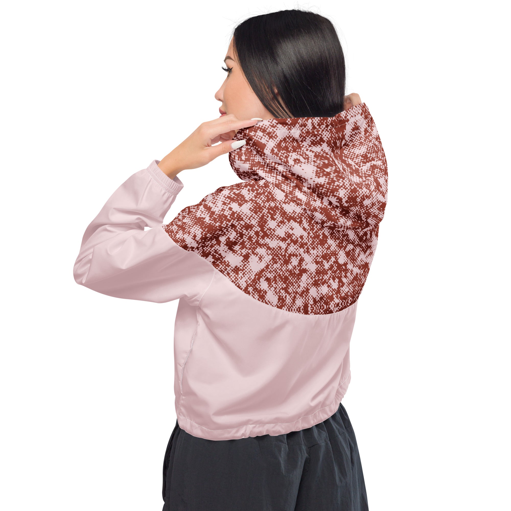 Woman wearing a pink windbreaker jacket with a patterned hood on a white background