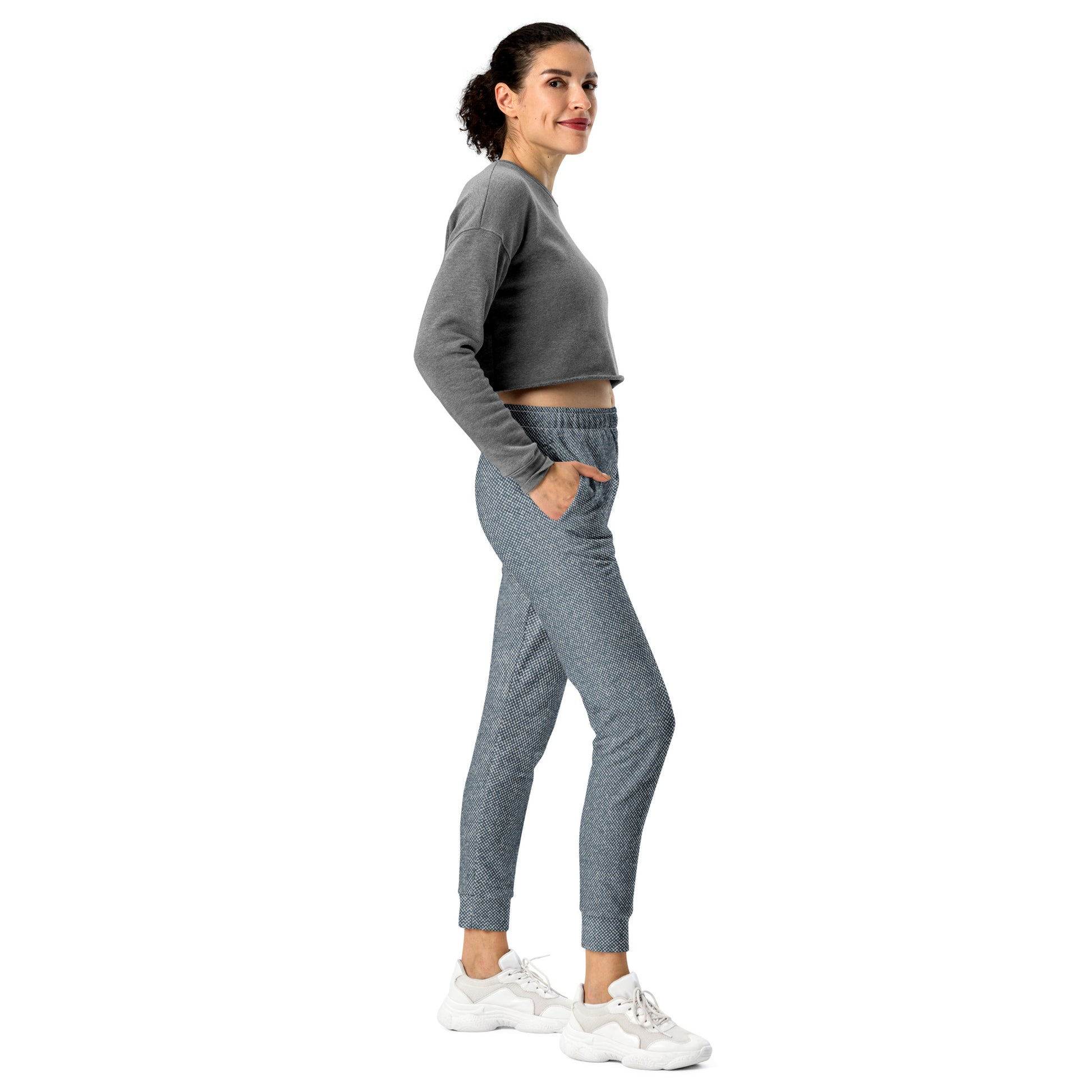 Woman wearing a gray long-sleeve top and blue slim fit joggers on a white background