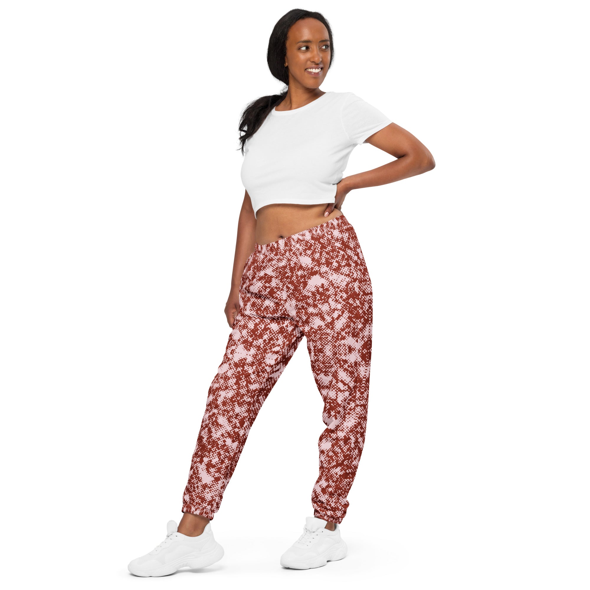 Woman wearing a white crop top and red track pants on a white background