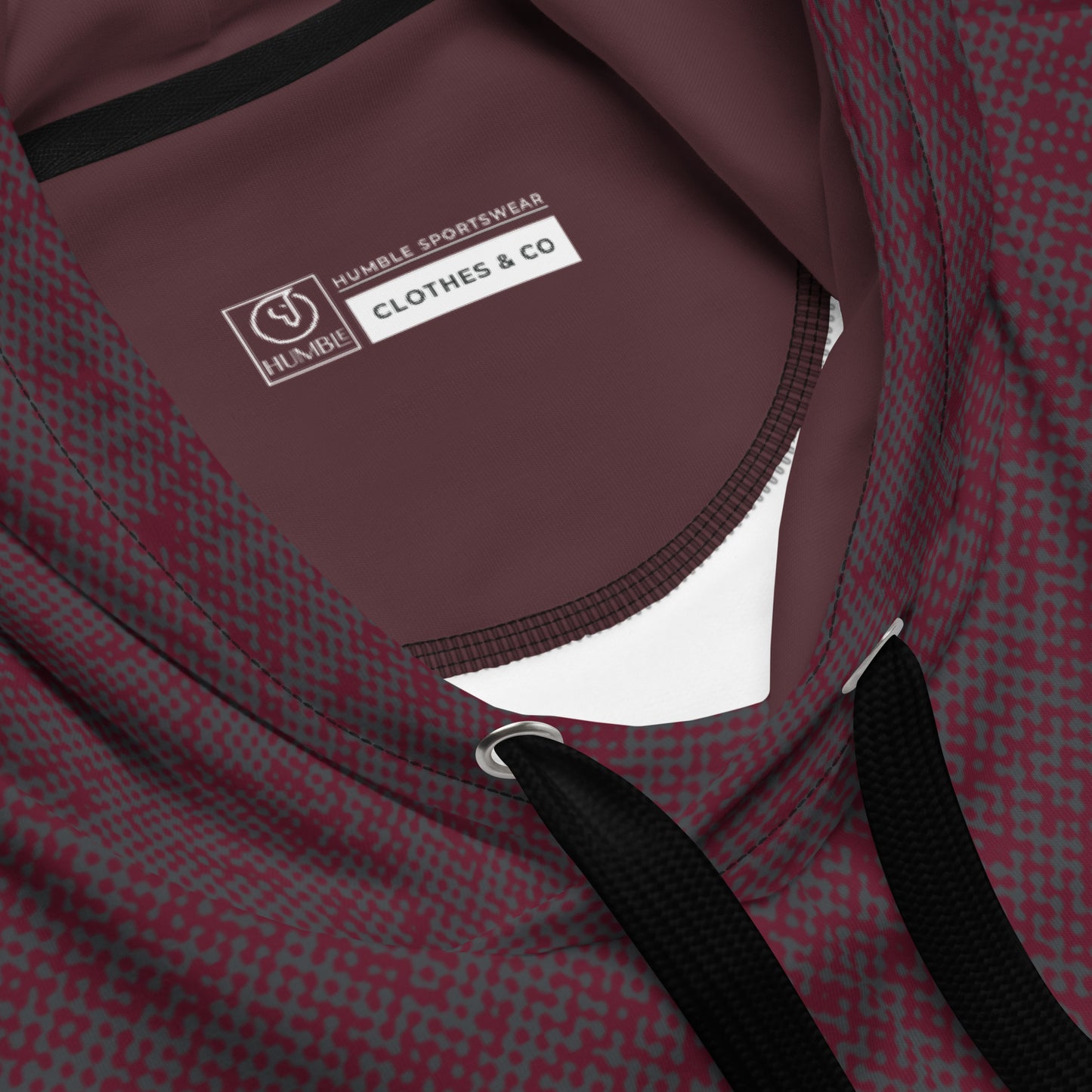 Close-up of a maroon relaxed fit hoodie with a visible brand label on a white background