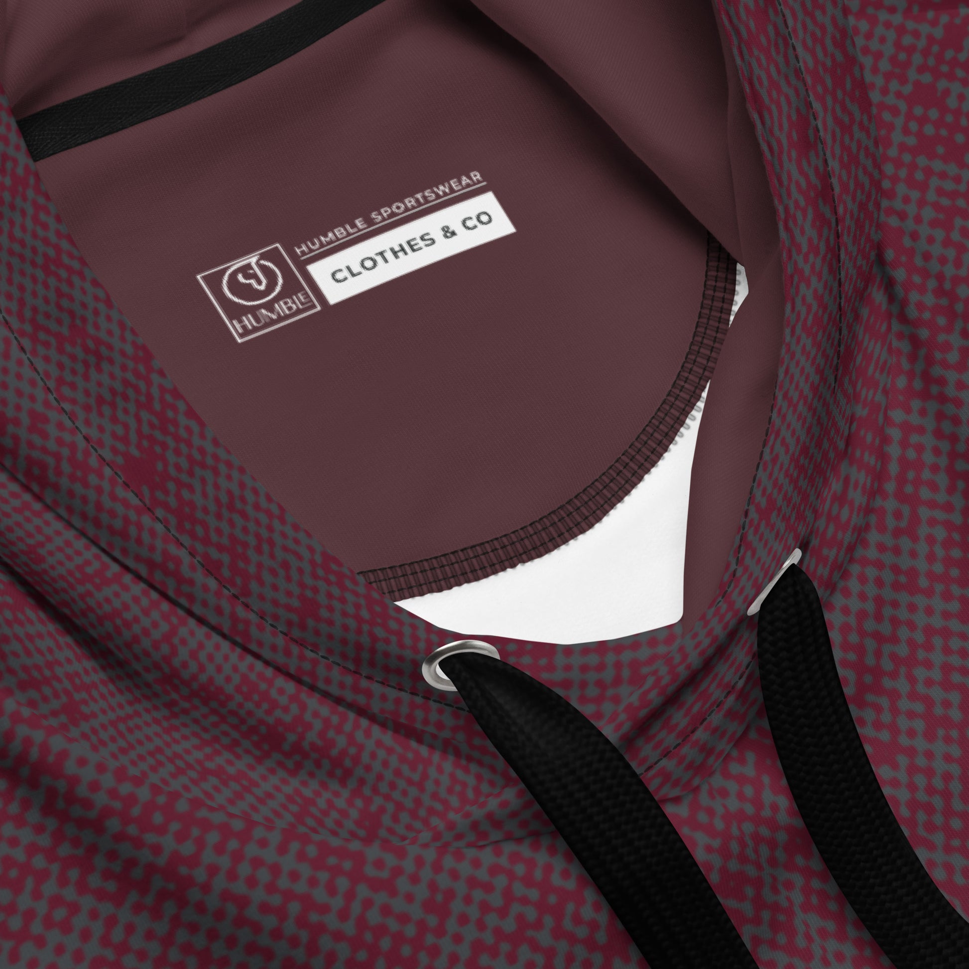 Close-up of a maroon relaxed fit hoodie with a visible brand label on a white background