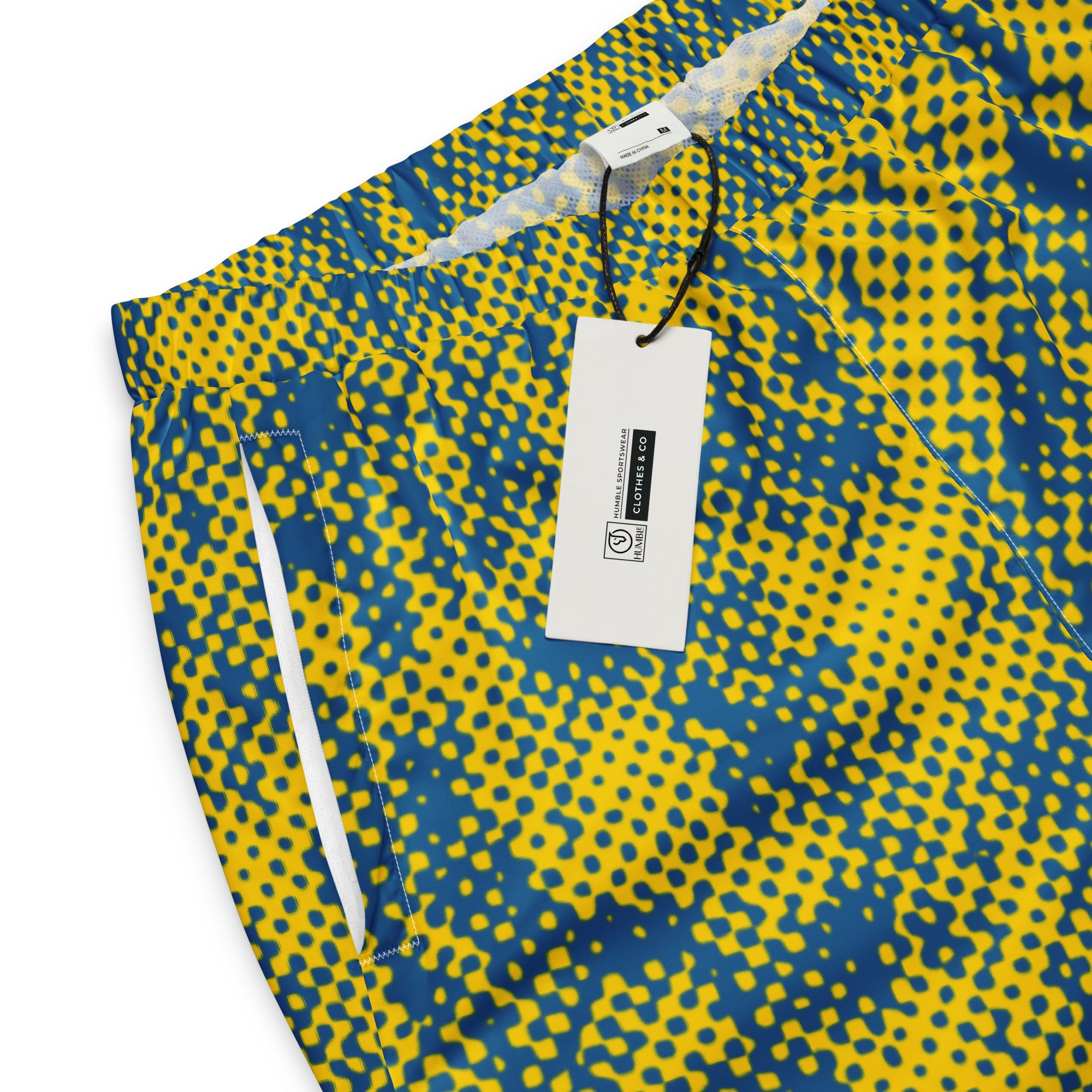 Yellow and blue patterned track pants with a tag on a white background