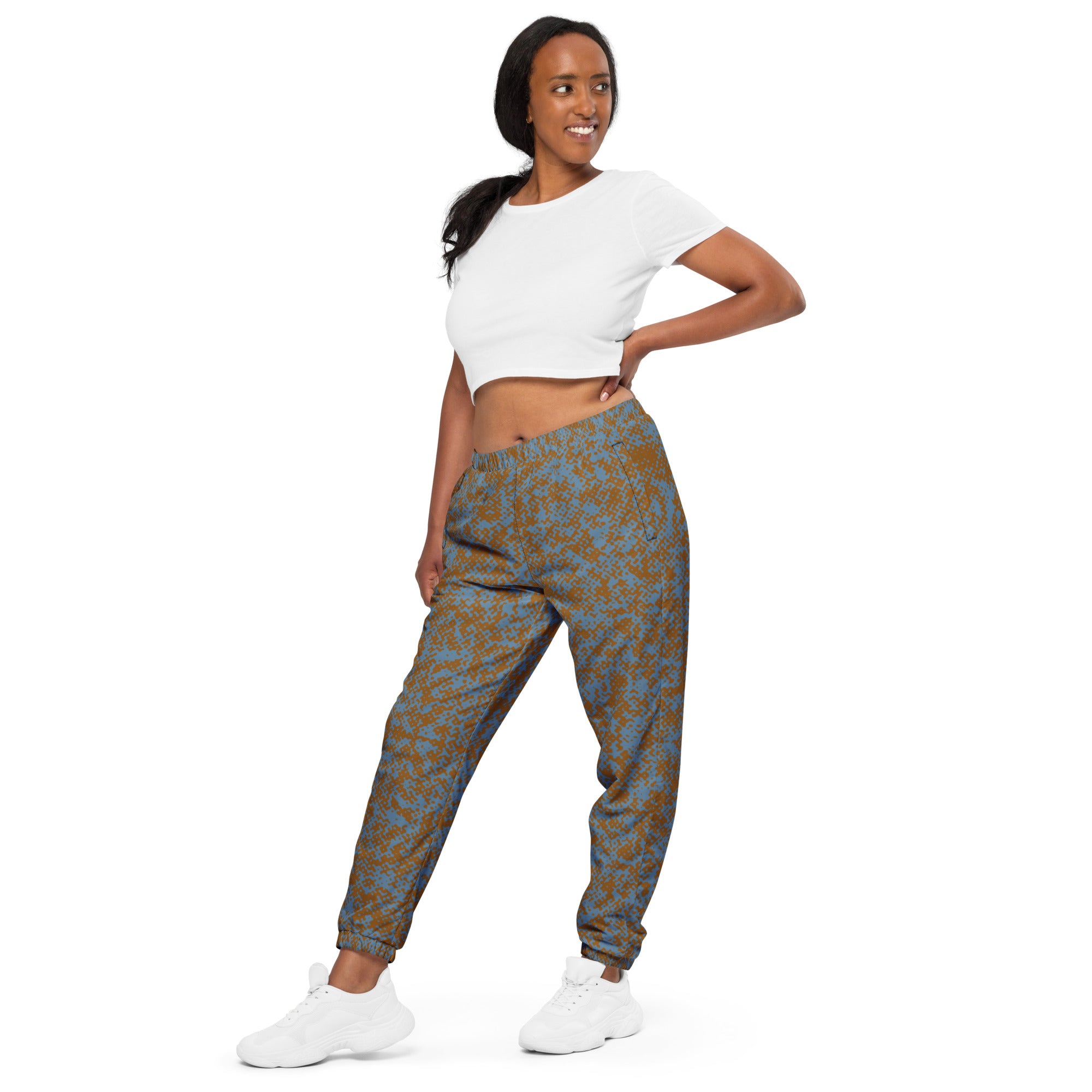 Woman wearing a white crop top and patterned track pants on a white background