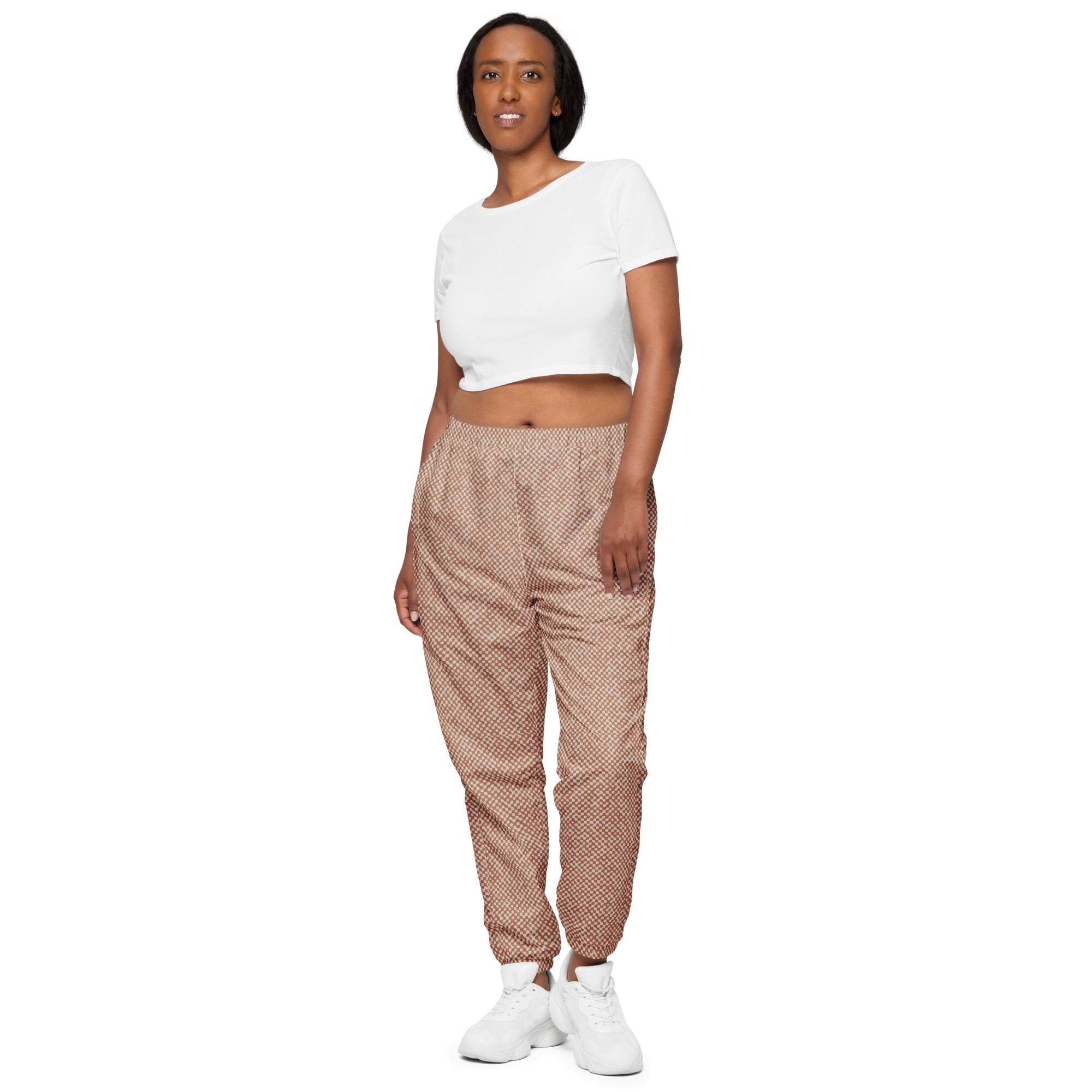 Woman wearing a white crop top and patterned track pants on a white background