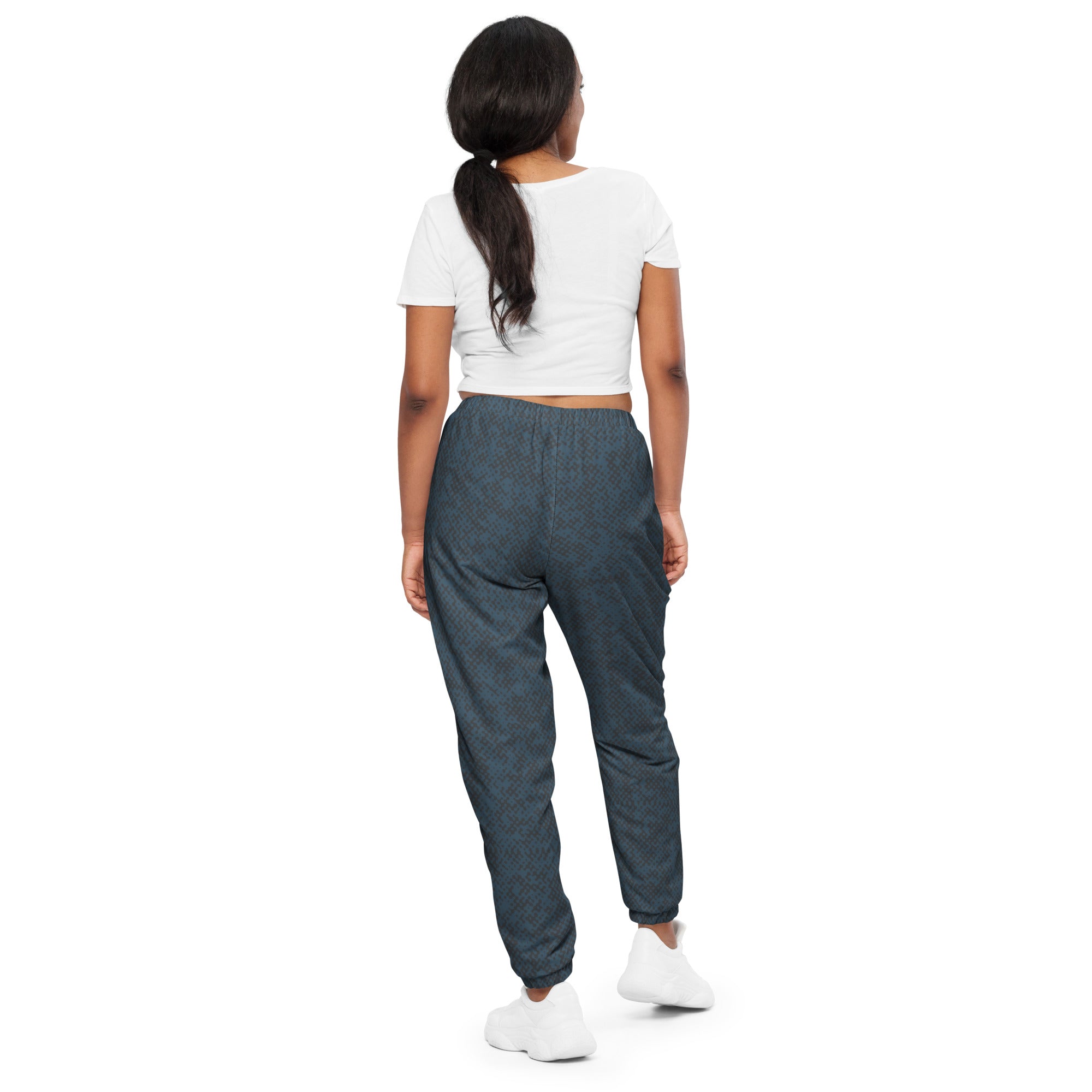 Person wearing a white crop top and navy blue track pants on a white background