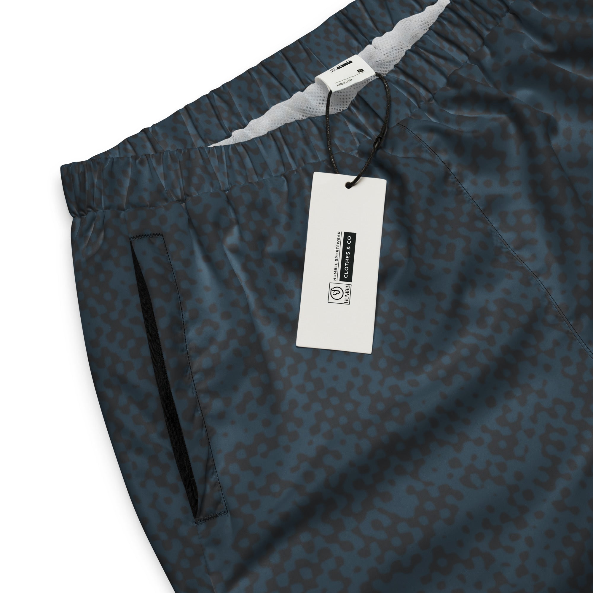 Navy blue patterned track pants with a tag on a white background