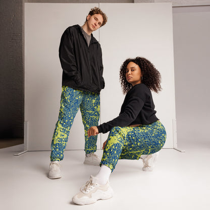 Two people wearing colorful patterned track pants in a studio setting.