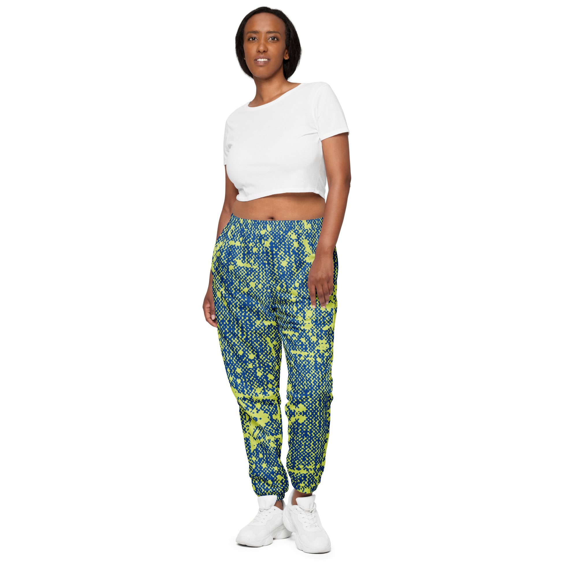 Woman wearing a pair of blue track pants with a geometric pattern, featuring an elastic waistband and ankle cuffs, with a mesh lining.